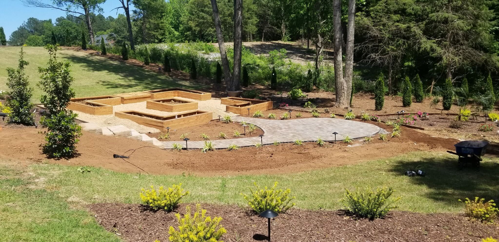 Finished backyard with raised planter beds, paver patio, and fresh plantings